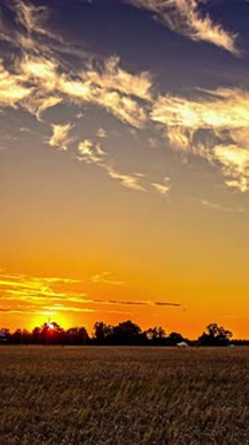 Dramatic Timelapse of Vibrant Sunset Over Tranquil Field with Clouds