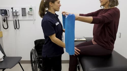 Physical therapist assists patient with resistance band exercise