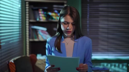 A Professional Woman is Intently Reading Important Documents in a Modern Office Setting