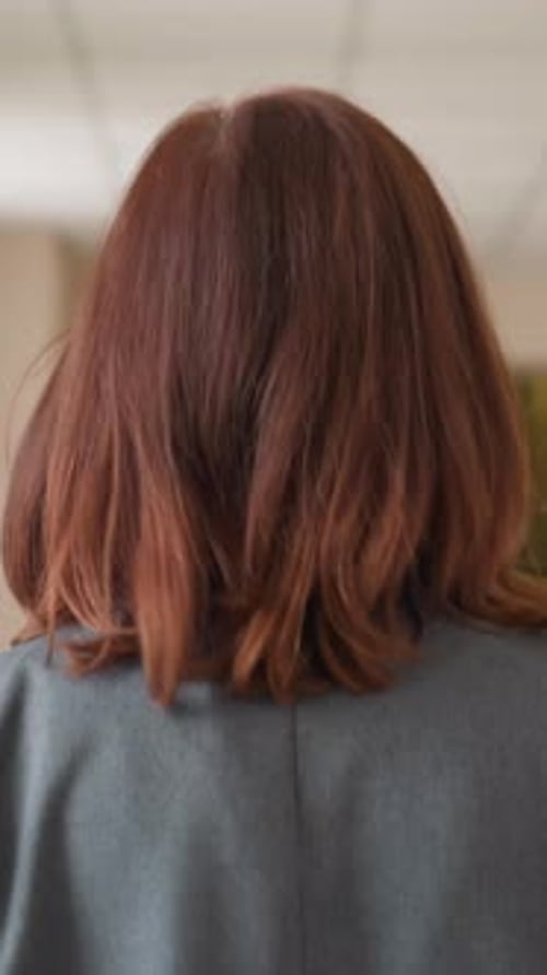 Close Up Back Shot of Woman Walking Purposefully in Modern Hallway Holding Red Folder