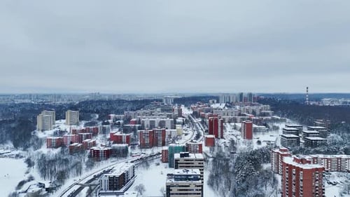 Drone flies over district of tall residential buildings in snowy winter