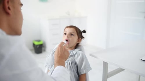 Doctor Examining Young Girl's Throat in Clinic