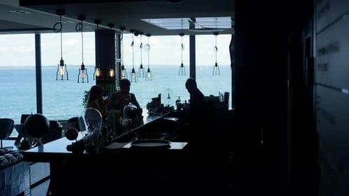 Silhouetted couple enjoying cocktails with ocean view at luxury hotel lounge