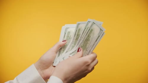 Hands Counting Cash Money on Yellow Background POV Close Up