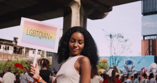 Young black woman with rainbow tattoo stickers and showing symbols of homosexuality in pride parade