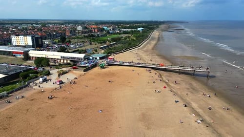 Skegness pier and beach Lincolnshire UK. Moving towards the pier showing sunbathers and the sea.