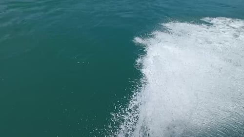 Mass of water displaced from a small boat at speed, in calm and blue sea, beautiful effect that wate