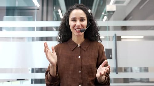 Webcam view. Smiling businesswoman in headset talking on video call looking at camera sitting