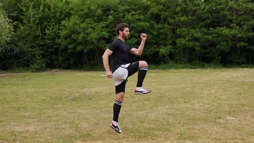 Side View of Confident Young Man in Full Soccer Gear Running Across Field