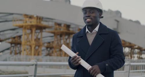 Slow Motion Portrait of African American Man Architect in Protective Helmet Standing in Construction