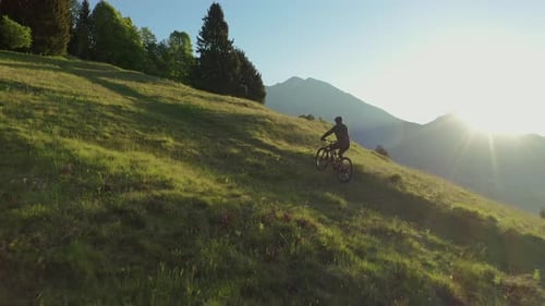 Drone passing a young athletic man on e-bike pedaling up the hill.