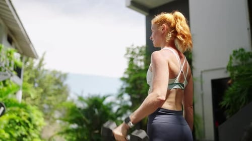 Fit Redhead Female Weightlifter Trains with Heavy Dumbbells in Outdoor Gym Strong Woman Performs