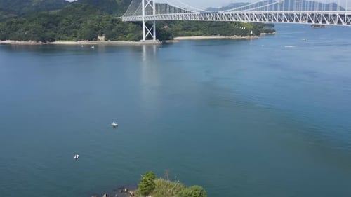 Aerial tilt reveals warm island scene at bridge in Hiroshima Japan