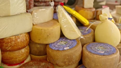 A yummy selection of yellow cheeses on a market stall, slow dolly away.