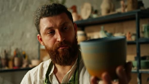 Ceramic Artist Inspecting Handmade Pottery in Workshop