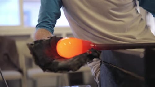 Glass Blower Shaping Molten Glass on Metal Rod