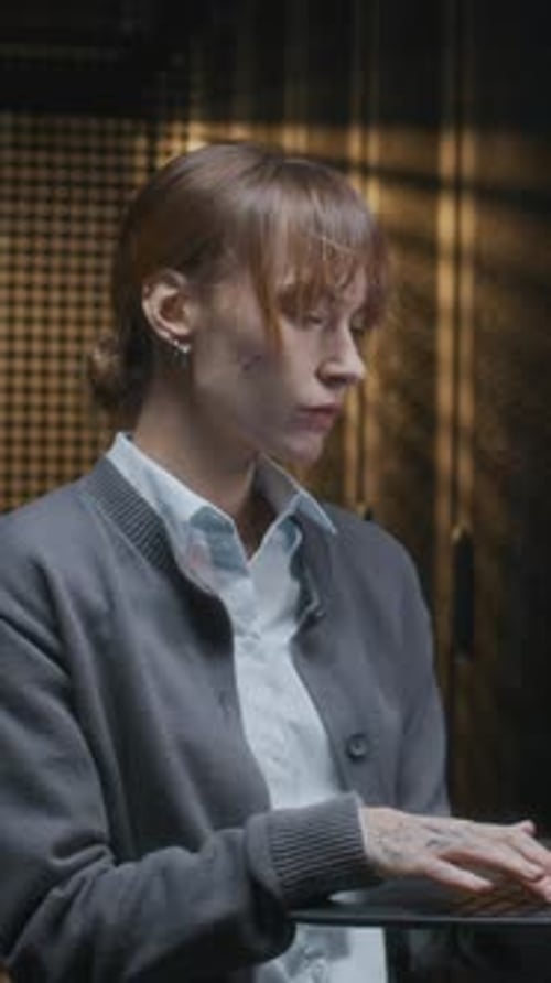 Vertical of Young Female IT Technician Coding on Laptop in Data Center