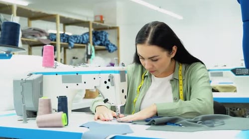 Porträt einer professionellen Näherin in einer Textilfabrik, die mit einer Industrienähmaschine näht