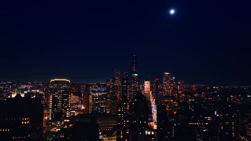 Flight above the vast cityscape of New York at night. The Moon is above the metropolis