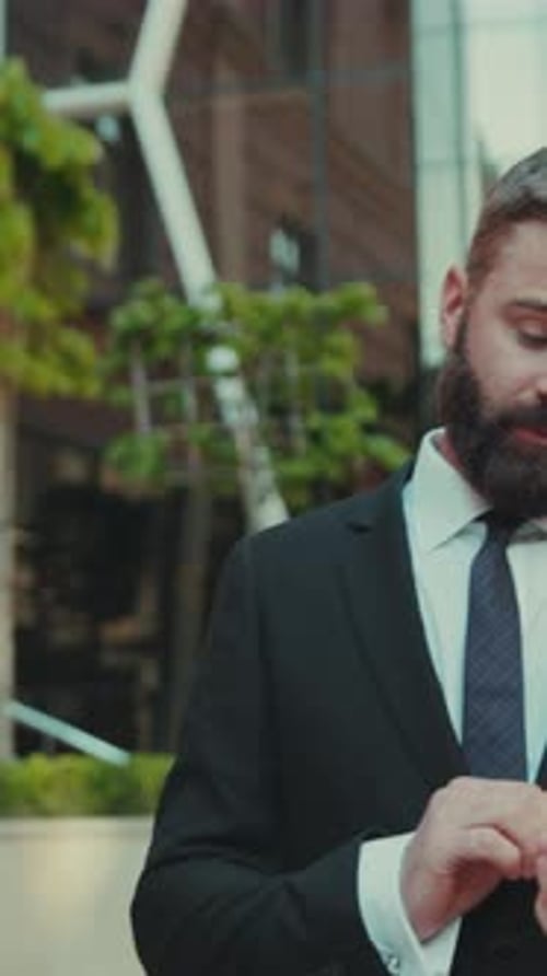 Portrait Successful Business Man Uses Smartphone While Walking on the Big City Business District