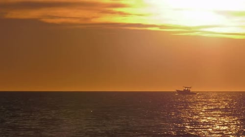 Motorboat on horizon with golden sunlight on water, mediterranean coast, spain