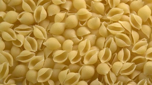 Italian pasta conchiglie rigate shell shaped rotating background closeup top view. Durum wheat
