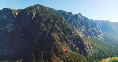 Pine trees covering the sunny side of huge rocks. Stunning mountains in Yosemite National Park
