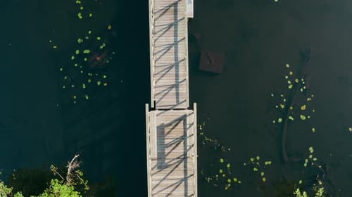 Drone Flies Over Wooden Old Boat Moored at Pier on Large Lake Among Forest