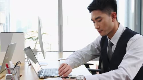 Konzentrierter, vielbeschäftigter junger Geschäftsmann, der auf dem Laptop tippt, online arbeitet und Notizen aus der Ferne schreibt, in der modernen Umgebung