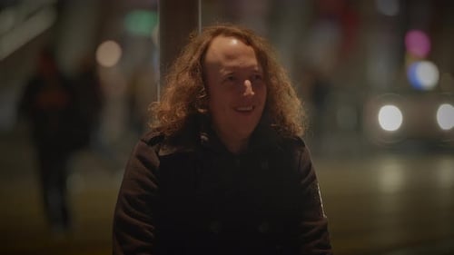 Man Smiling on Busy City Street at Night