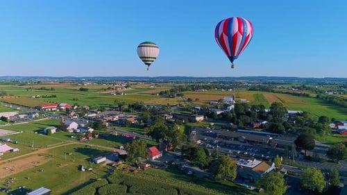 An Aerial View of Multiple Hot Air Balloons Floating in the Sky During a Festival With Crowds