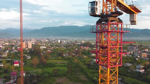 Construction crane machinery on hill, mountains in background. View from drone.