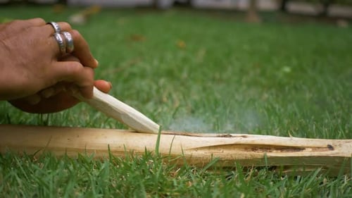 A man is attempting to ignite a fire by using an ancient technique that includes placing a big piece