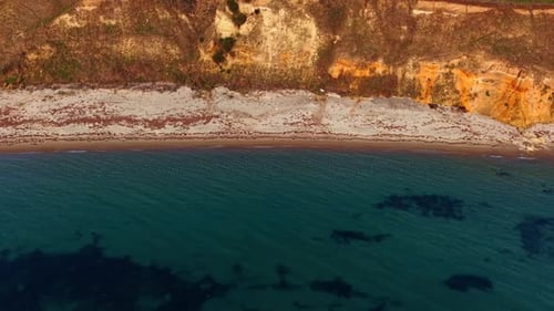 Flying over sea-green water at the rocky coast.