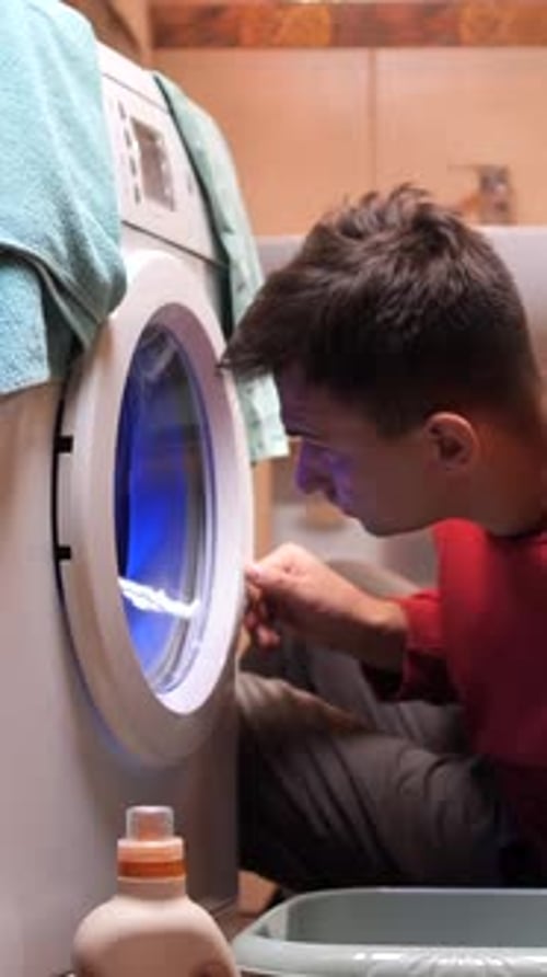 Young Adult Examining Washing Machine in Bathroom