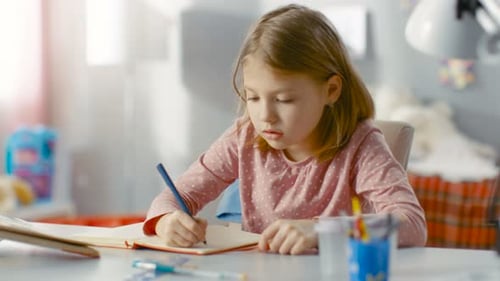 Girl Writing in Notebook at Desk at Home