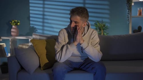 Depressed Young Man with Hand on Face Looking Blank at Home All Day.