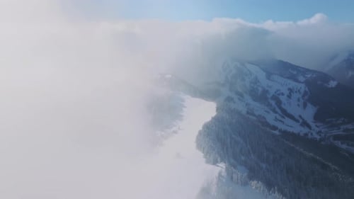 Filmmusik Luftdrohne, die durch weiße Wolken über den Winterbergen fliegt