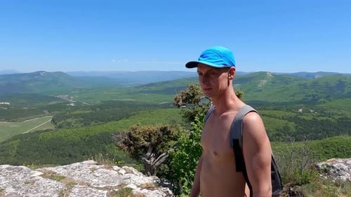 Smiling Young Shirtless Man Walking on Rocky Mountain Against Sky
