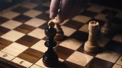 Fingers move queen to checkmate and lay down king on chessboard, close-up