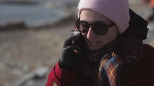 Pretty Woman Wearing Maroon Jacket and Beanie Hat Talking To Phone While Walking On The Street Near