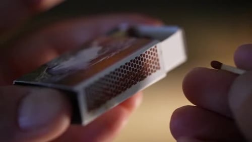 Hand Strikes Match on Matchbox in Macro Shot