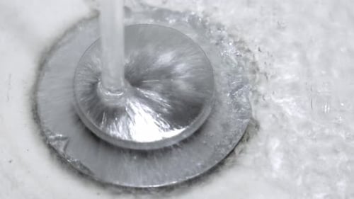 Fluxo de água fluindo para o ralo branco da pia