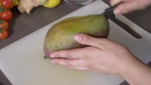 Hands Slice Ripe Mango With Sharp Knife