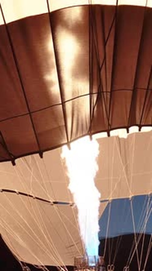 Vertical video. The launch of a large hot air balloon, close-up, with the flames filling it with hot