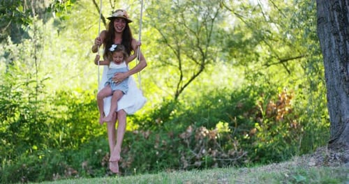 Woman and Child Swinging on Tree Swing in Nature