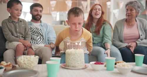 Boy Blows Out Birthday Candles with Family
