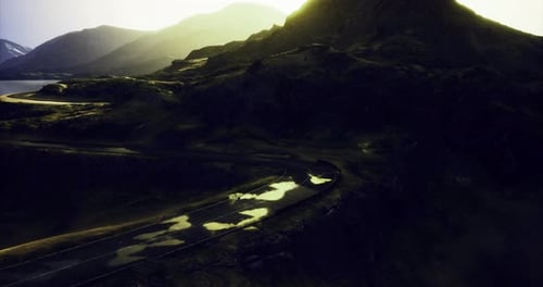 Winding Road Through Mountainous Landscape at Sunset Creating Serene Beauty