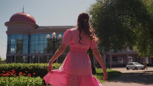 Caucasian Lady Enjoys Leisurely Walk By Flowers and Architecture Woman in Pink Explores Garden Area