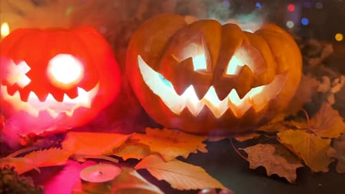 Traditionelle geschnitzte Kürbisse, die innen im Rauch glühen, liegen auf dem Tisch zwischen Halloween-Dekorationen